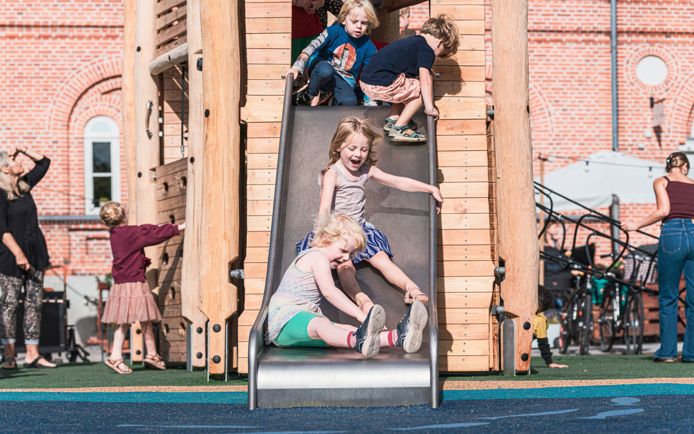 Børn rutcher ned af en rutchebane på en legeplads