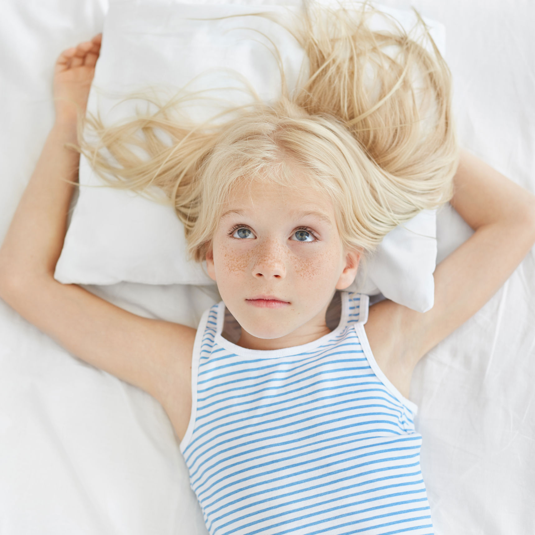 En lyshåret pige ligger i en seng