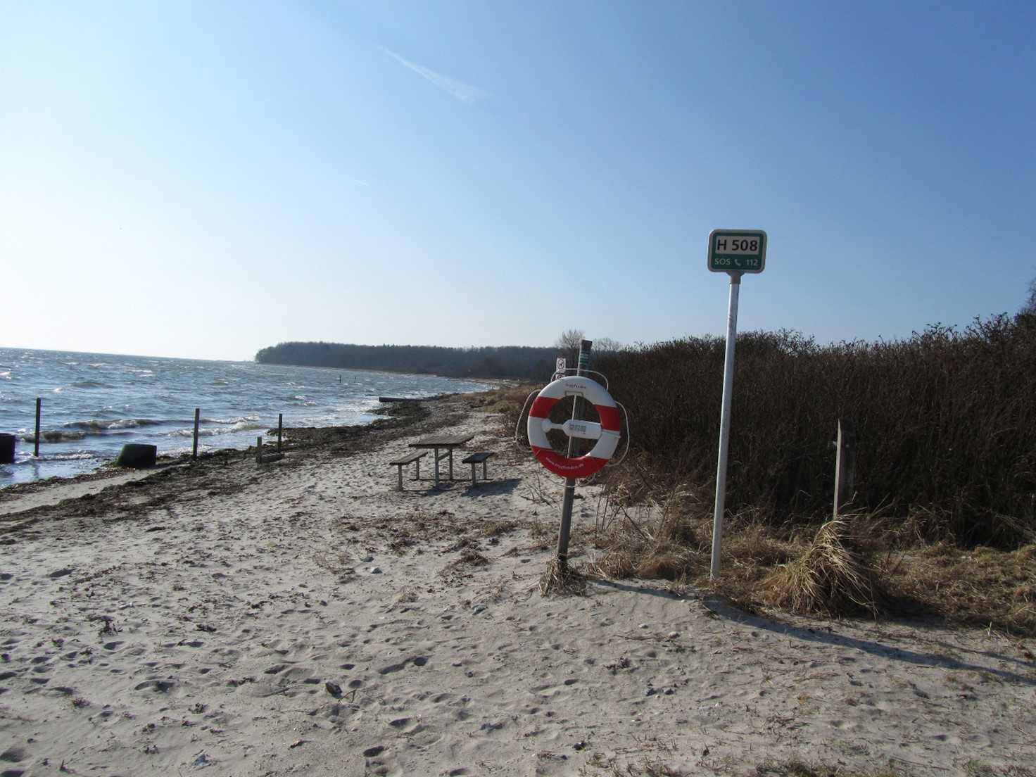 Stranden ligger naturskønt ved et offentligt grønt område med plads til ophold og med udsigt til Langeland.