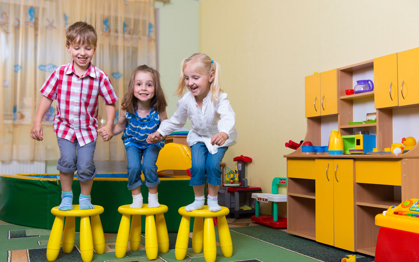 Tre børnehavebørn hopper fra hver deres skammel