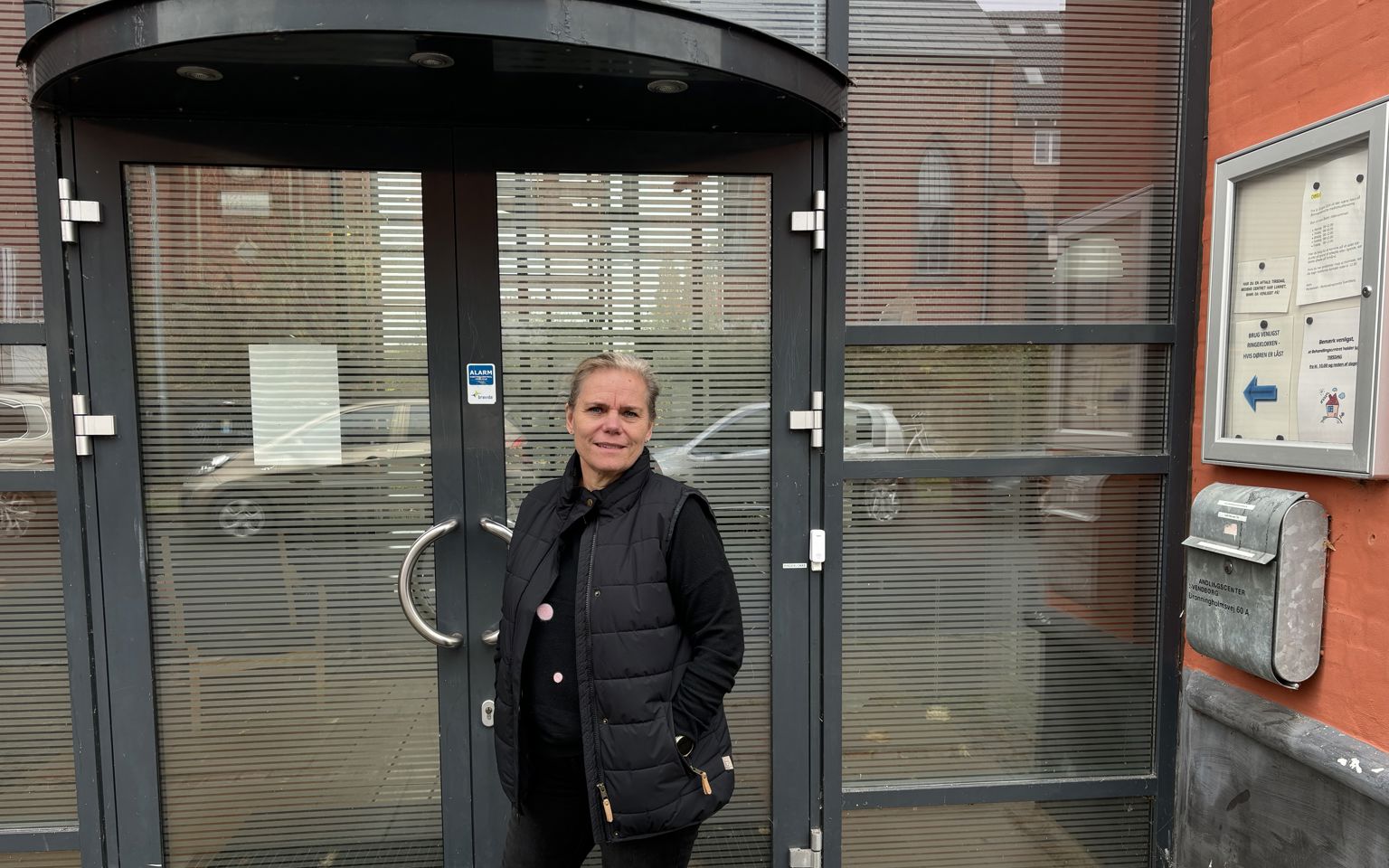 Kvinde i mørt tøj står foran en indgangsdør