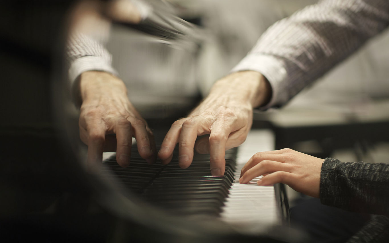 Underviser spiller klaver sammen med elev