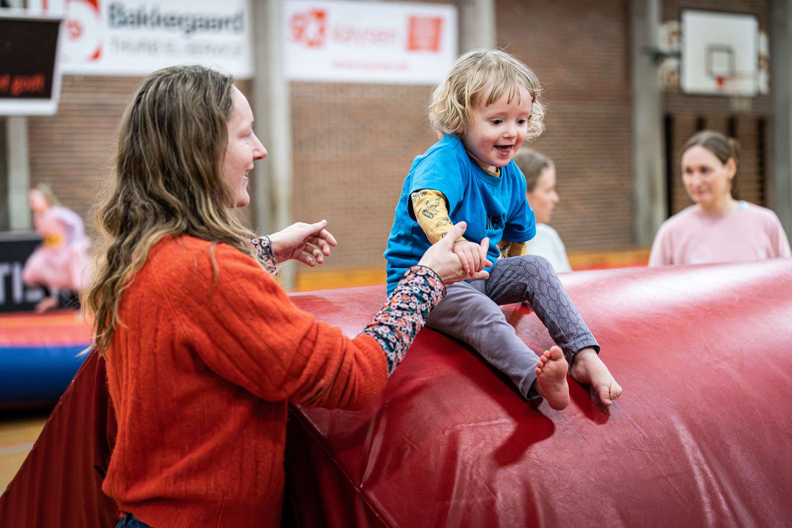 Gymnastik i SG-Huset - en voksen hjælper sit barn i spring fra høj madras