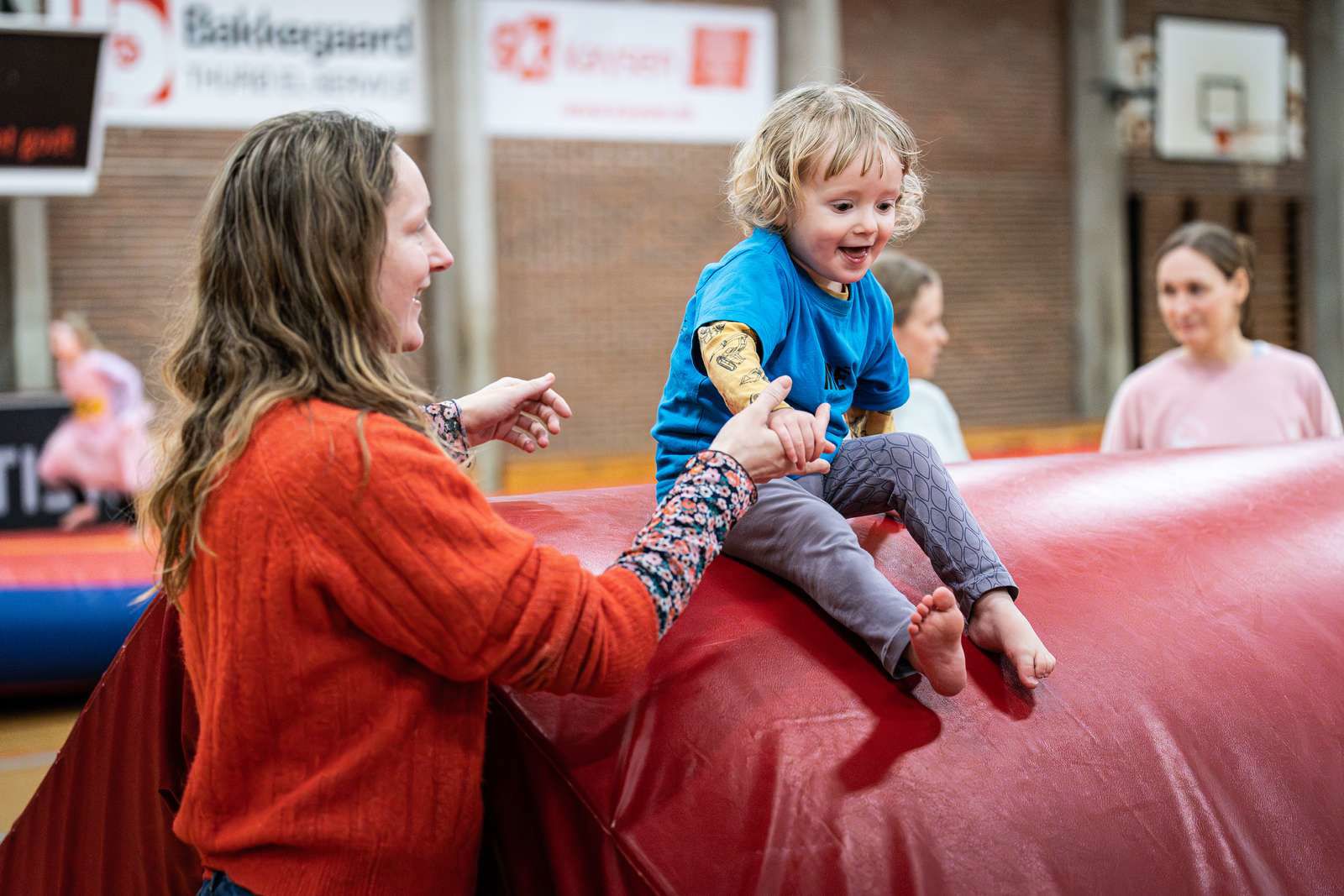 Gymnastik i SG-Huset - en voksen hjælper sit barn i spring fra høj madras