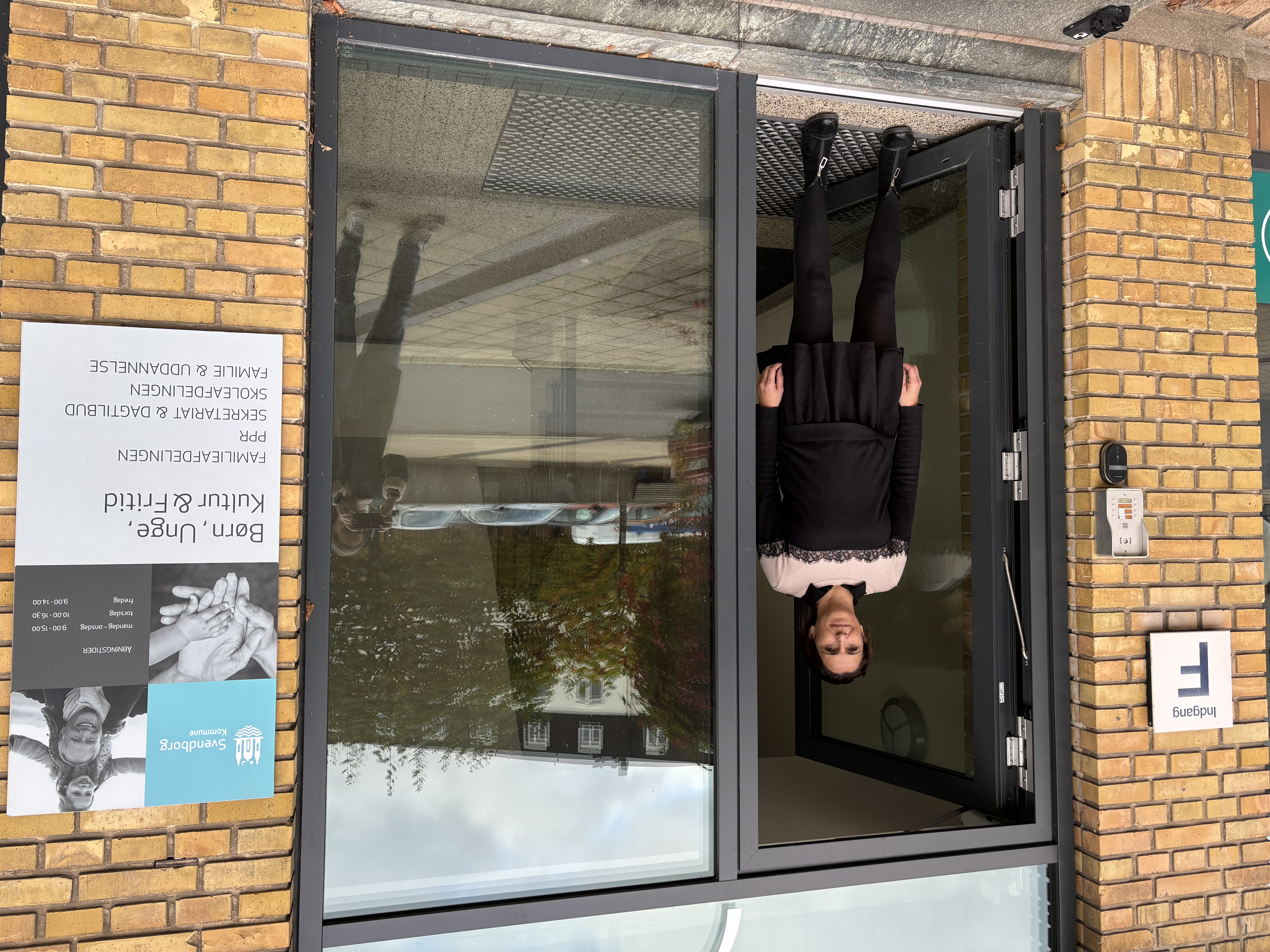 Kvinde står i indgangsdør af glas