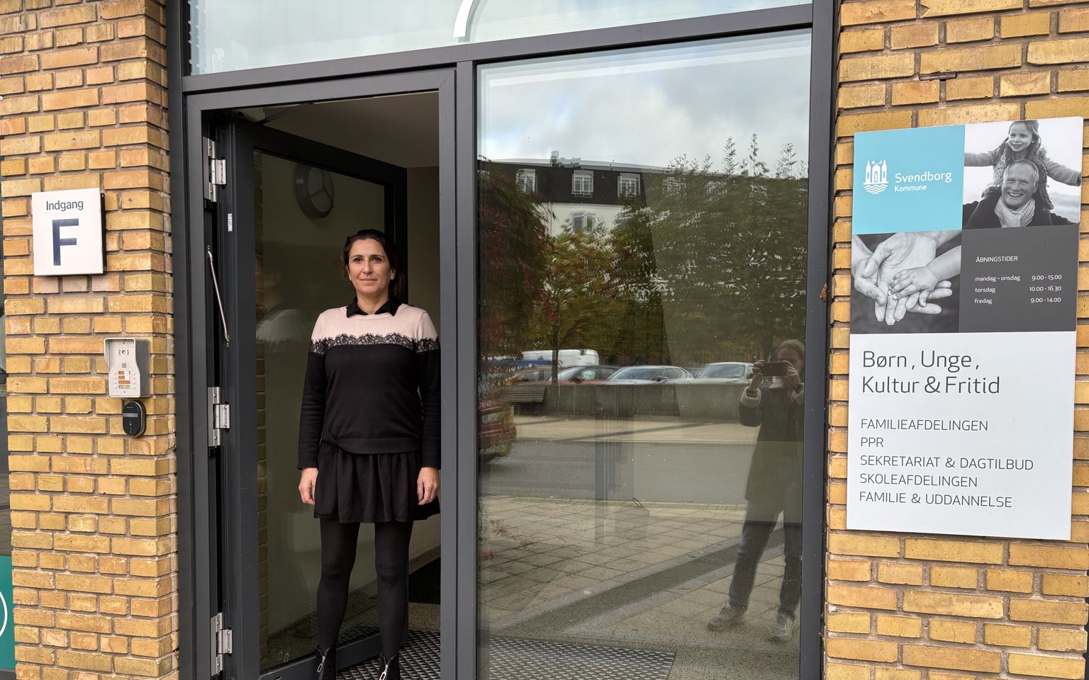 Kvinde står i indgangsdør af glas