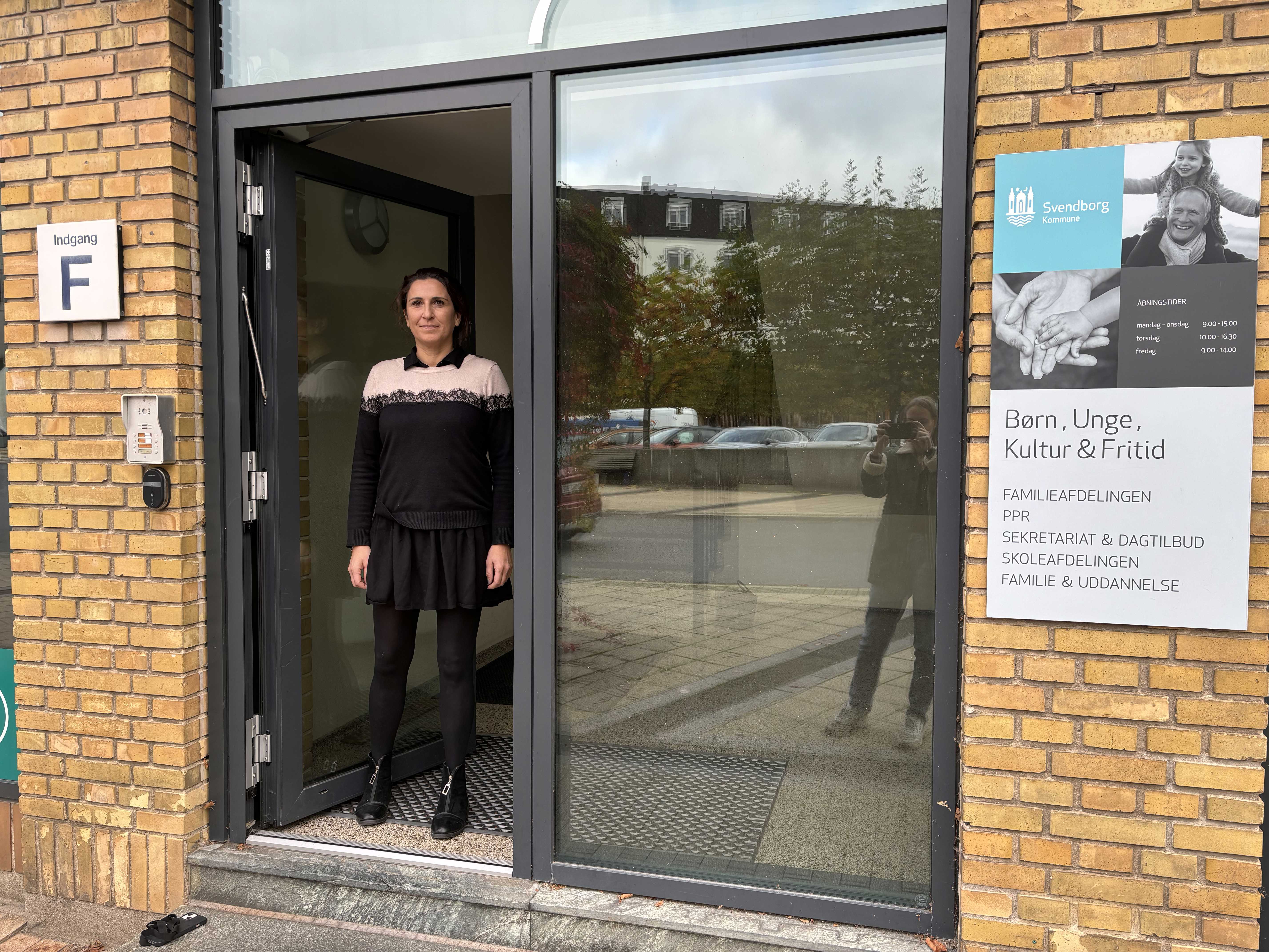 Kvinde står i indgangsdør af glas