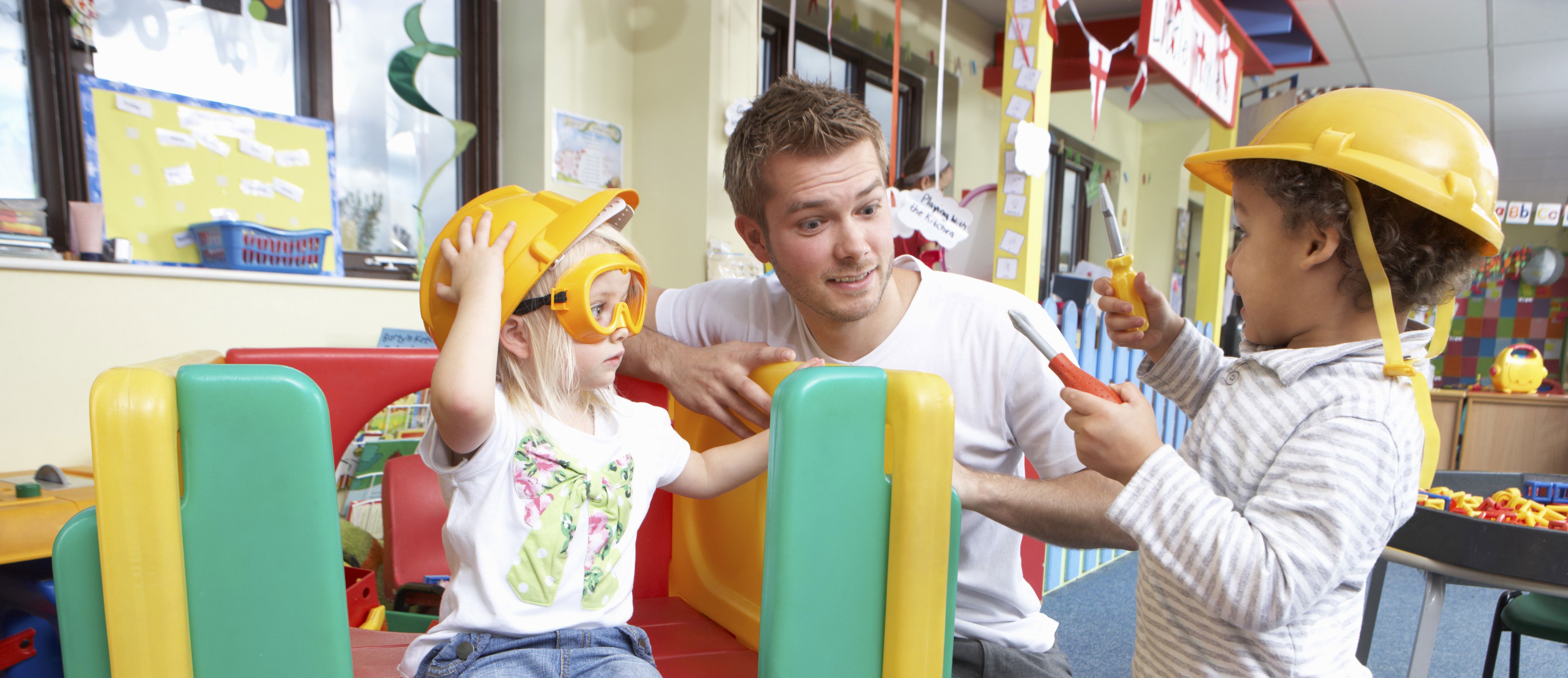 To børn som leger sammen med en mandlig pædagog